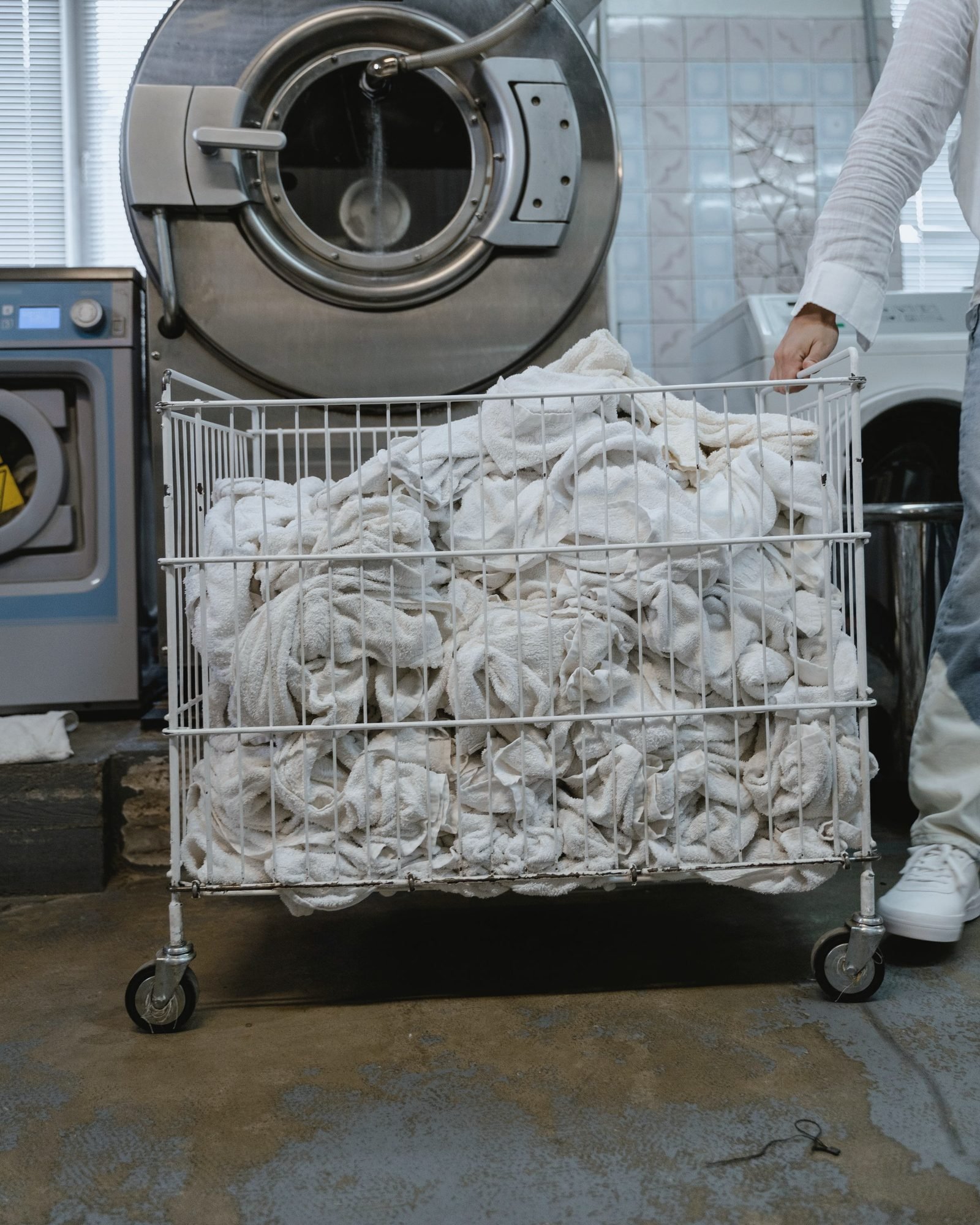 Wire cart heaped with soiled white linens being wheeled away